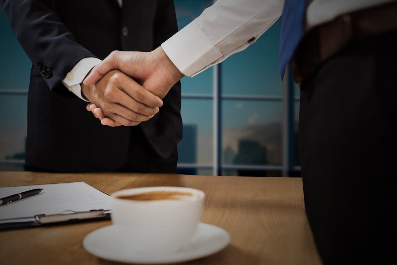 Two business professionals shaking hands across a desk